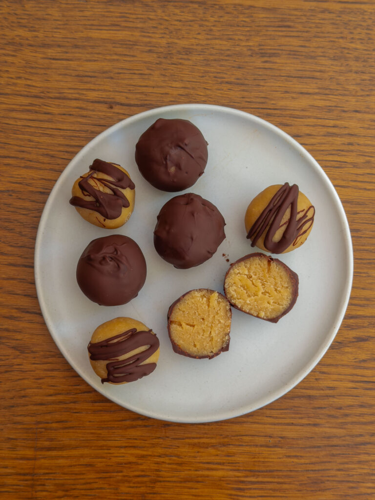 Gesunde Cottage Cheese Protein Balls mit Schokoglasur auf einem Teller serviert, angeschnitten zur Hälfte Mrs Flury