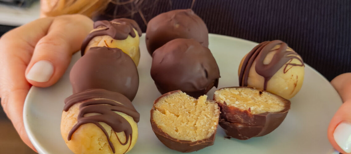 Gesunde Cottage Cheese Protein Balls mit Schokoglasur auf einem Teller serviert, angeschnitten zur Hälfte Mrs Flury
