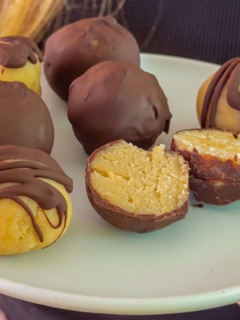 Gesunde Cottage Cheese Protein Balls mit Schokoglasur auf einem Teller serviert, angeschnitten zur Hälfte Mrs Flury